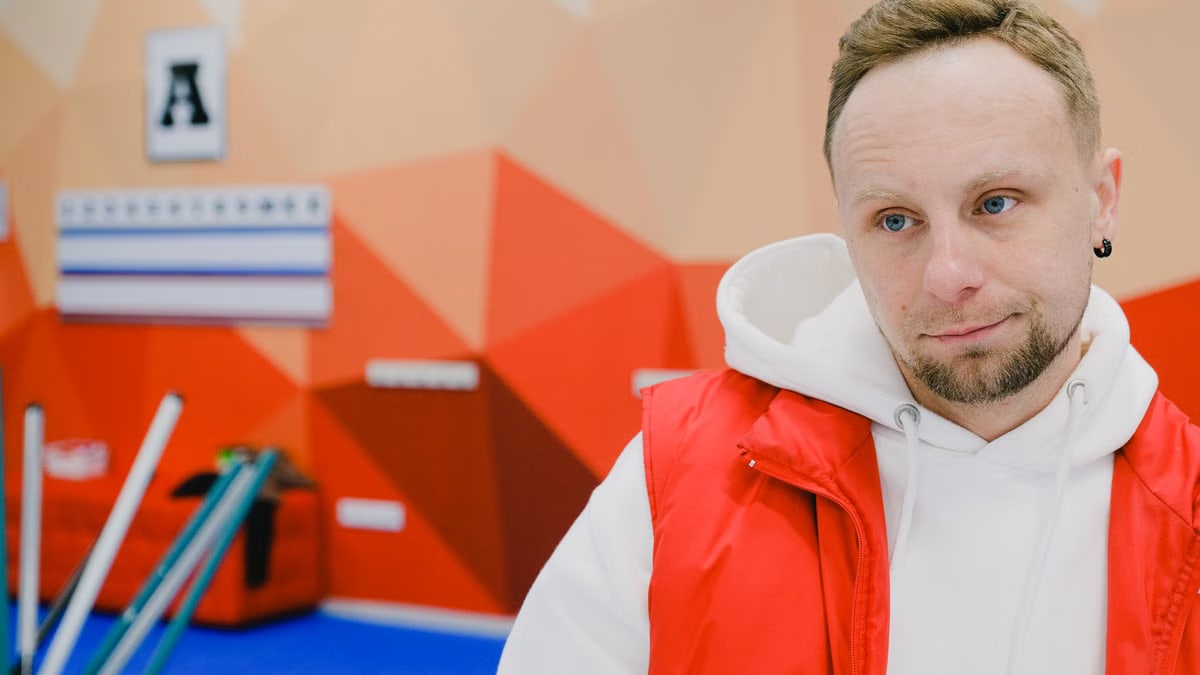 Serious male curling player in sportswear looking away with pensive face while standing near brooms and score board during game